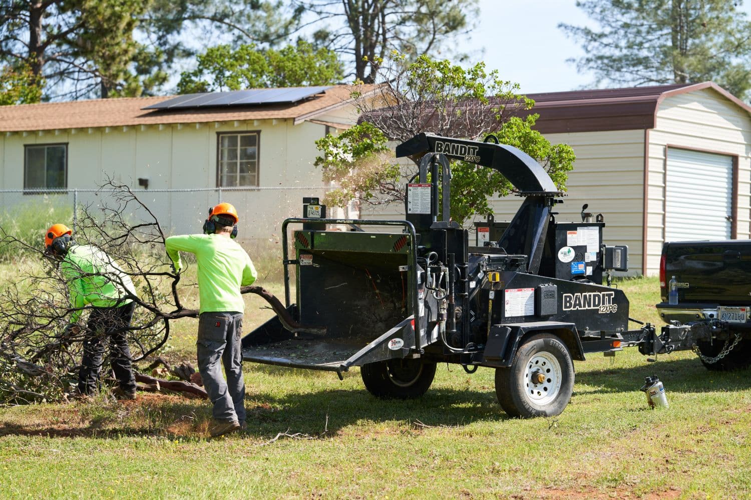 BCFSC chipper crew feeding brush into a wood chipper